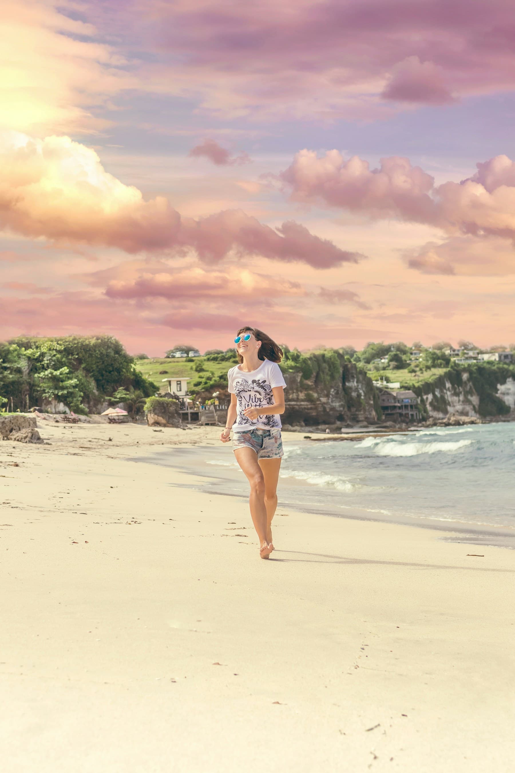 A smiling woman moving along a sunny beach